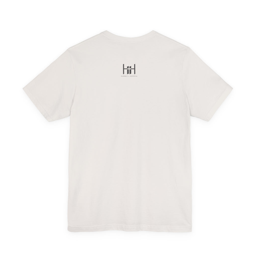 A white short-sleeve crewneck t-shirt with a small black 'Humble + Hopeful' logo printed on the upper chest, displayed against a solid white background.