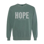 A muted blue spruce crewneck sweatshirt featuring the word 'HOPE' printed across the chest in a white patterned font, with 'HUMBLE + HOPEFUL' written underneath.