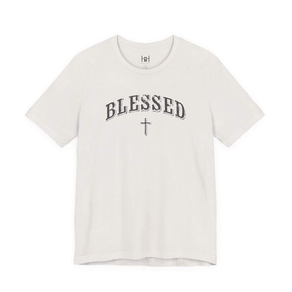 A white short-sleeve crewneck t-shirt featuring the word 'BLESSED' in an arched, distressed black font with a matching cross underneath, displayed on a clean white background.