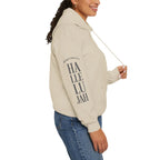 Person wearing a sand colored hoodie with 'Hallelujah' on the sleeve on a white background