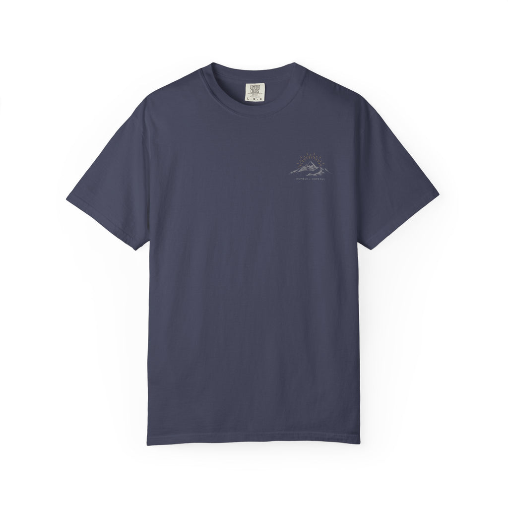 Denim color t-shirt with small mountain design and 'humble and hopeful' text on a white background.