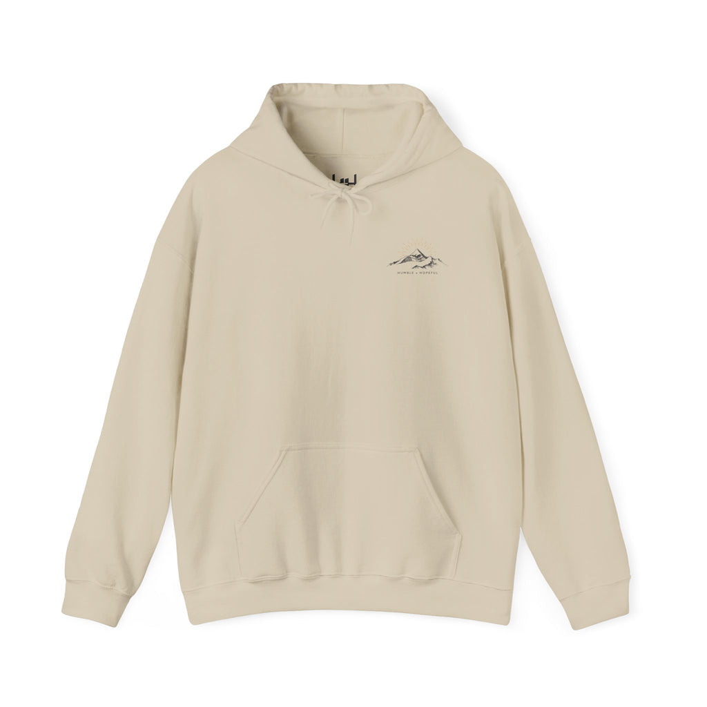 Beige pullover hoodie with a small mountain and humble and hopeful text on a white background.