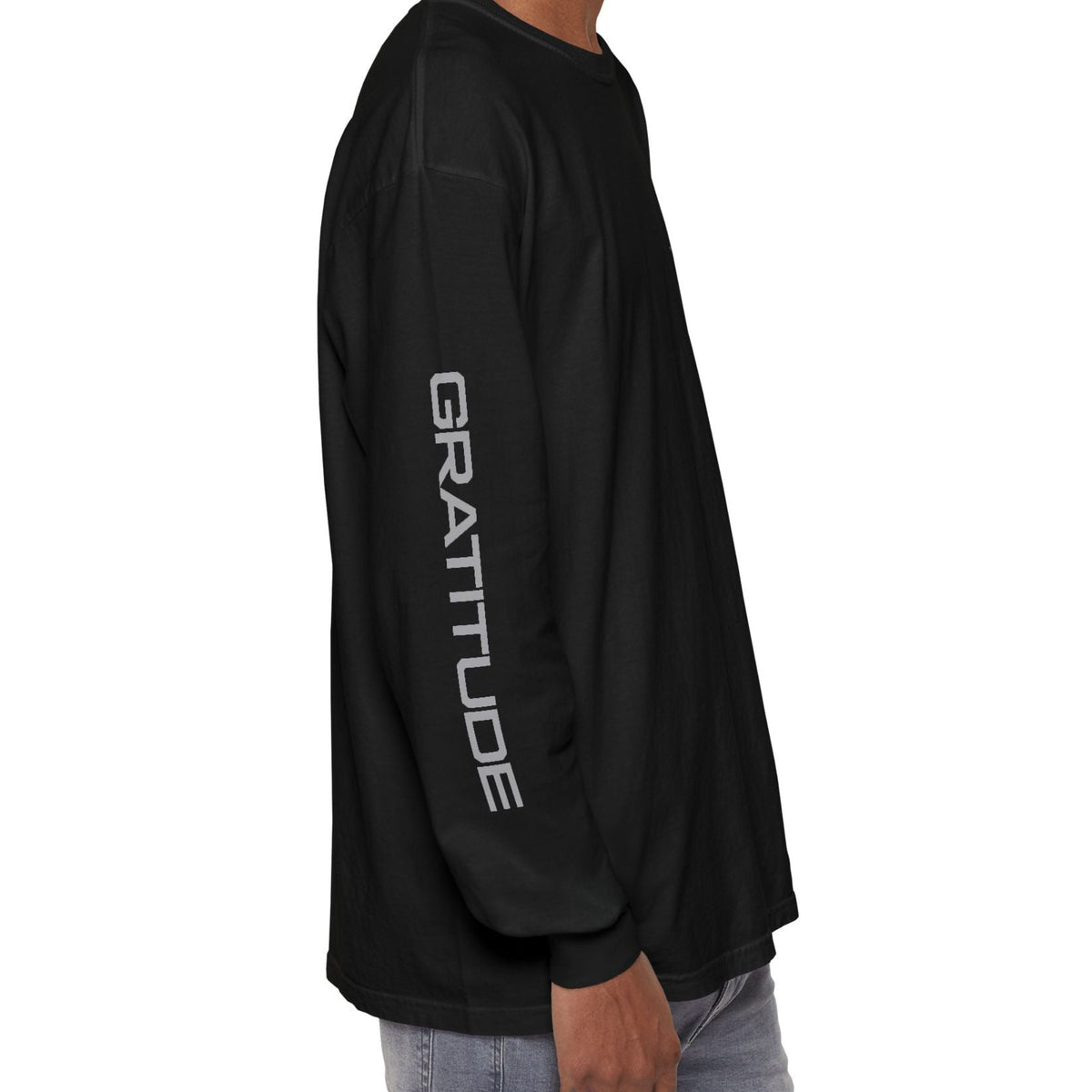 A man wearing a black long-sleeve t-shirt with 'GRATITUDE' printed vertically in white on the left sleeve, shown from a side profile view against a plain white background.