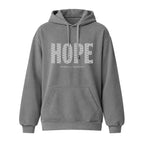 A gray pullover hoodie with a front kangaroo pocket and drawstrings, featuring the word 'HOPE' in a textured white pattern across the chest, with the smaller text 'HUMBLE + HOPEFUL' underneath.