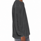 A man shown from the side wearing a dark charcoal gray long-sleeve t-shirt with 'RENEWED' printed vertically in black on the left sleeve, paired with light blue jeans against a plain white background.