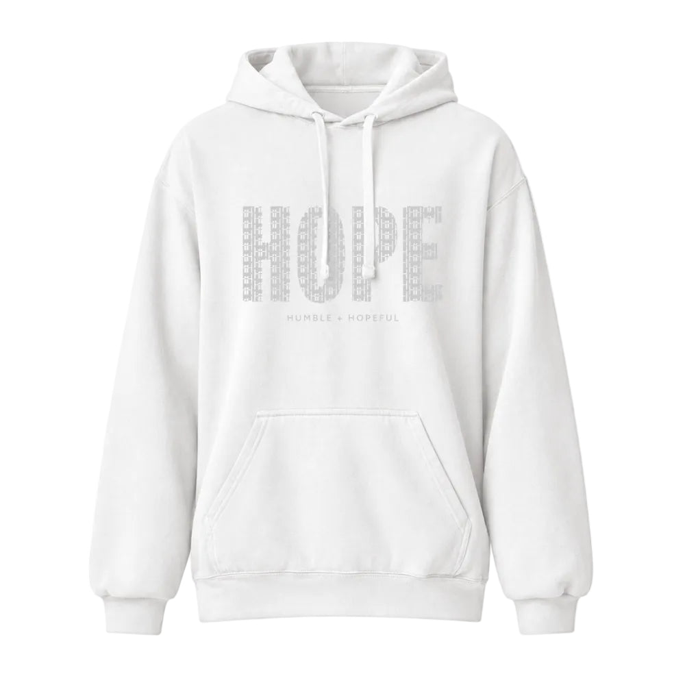 A white pullover hoodie with a front kangaroo pocket and drawstrings, featuring the word 'HOPE' printed in a textured gray pattern across the chest, with the smaller text 'HUMBLE = HOPEFUL' underneath.