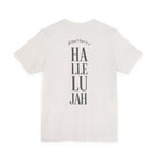 An off-white short-sleeve t-shirt shown from the back, featuring a vertical graphic print that reads 'all that I have is a Hallelujah' in dark gray text.