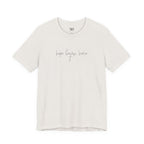 An off-white short-sleeve crewneck t-shirt with the phrase 'hope began here' printed in a thin gray cursive font across the chest. The shirt is displayed flat against a solid white background.